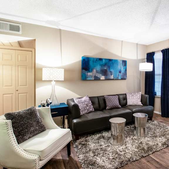 A living room with a black couch and a white chair.