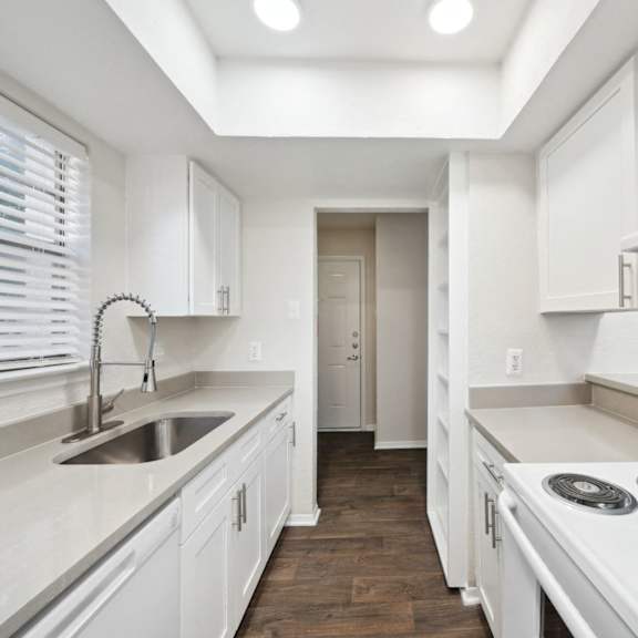 a white kitchen with white appliances and white cabinets at woodlands of plano in plano, tx