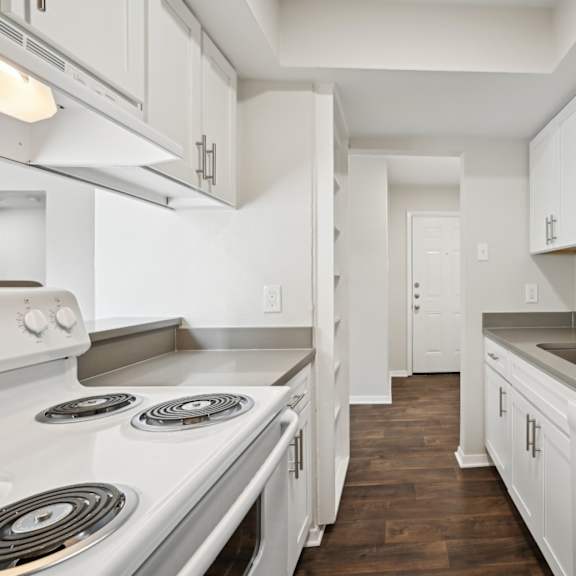 an empty kitchen with white cabinets and appliances and a sink at woodlands of plano in plano, tx