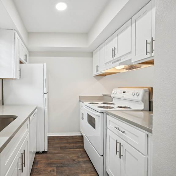 a white kitchen with white appliances and white cabinets at woodlands of plano in plano, tx