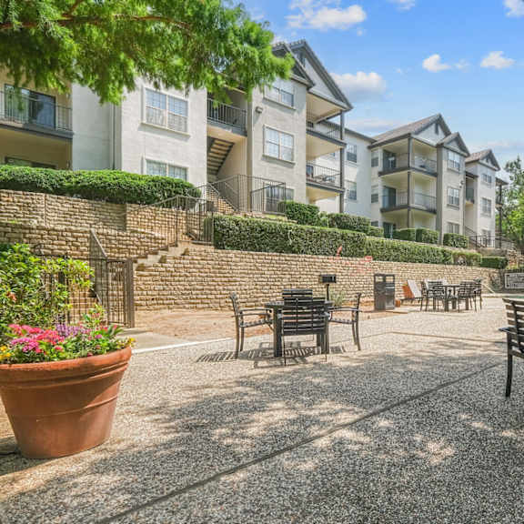 an al fresco dining patio with tables and chairs at jefferson place apartments in irving, tx