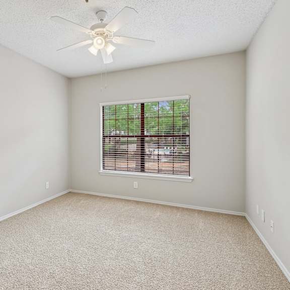 b2 bedroom with a ceiling fan and a window at jefferson place apartments in irving, tx
