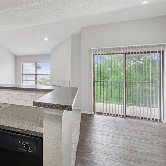 b2 kitchen overlooking living room and sliding door to private balcony at jefferson place apartments in irving, tx