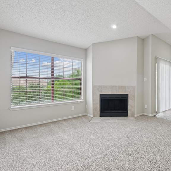 b2 living room with a fireplace and a large window at jefferson place apartments in irving, tx