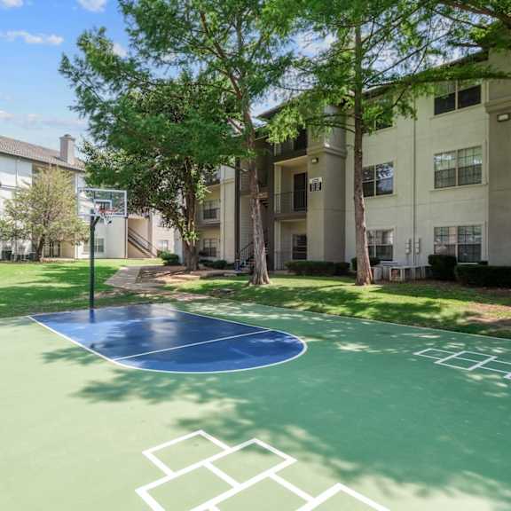 a basketball court and hopscotch area surrounded by apartment buildings at jefferson place apartments in irving, tx