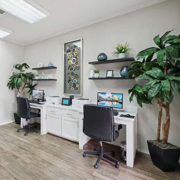 a business center with computers, printers, and potted plants at jefferson place apartments in irving, tx