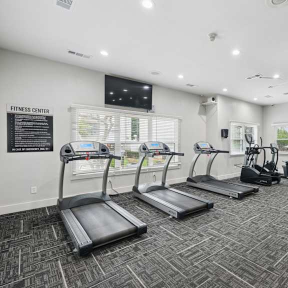 a fitness center with treadmills and strength training machines at jefferson place apartments in irving, tx