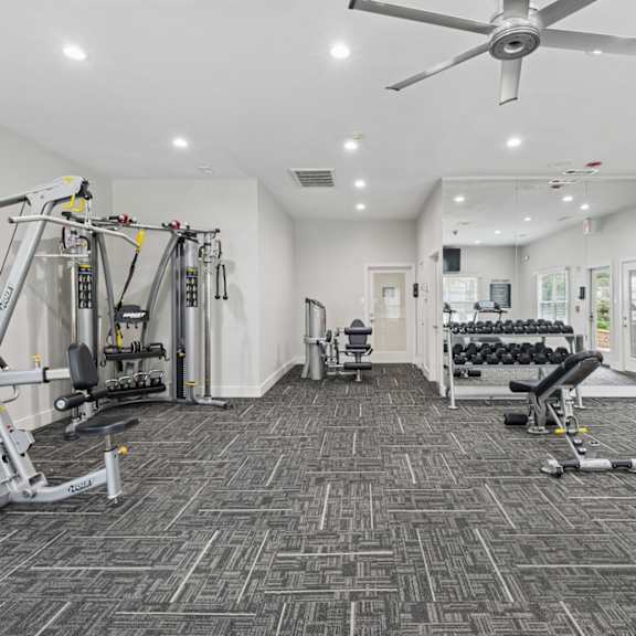 a spacious fitness center with a variety of equipment including treadmills and strength training machines at jefferson place apartments in irving, tx