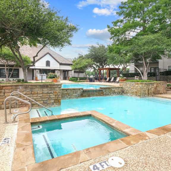 a sparkling pool surrounded by lush trees at jefferson place apartments in irving, tx