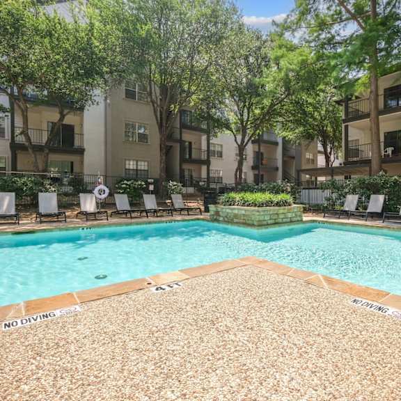 sparkling pool surrounded by apartment buildings and pool loungers at jefferson place apartments in irving, tx