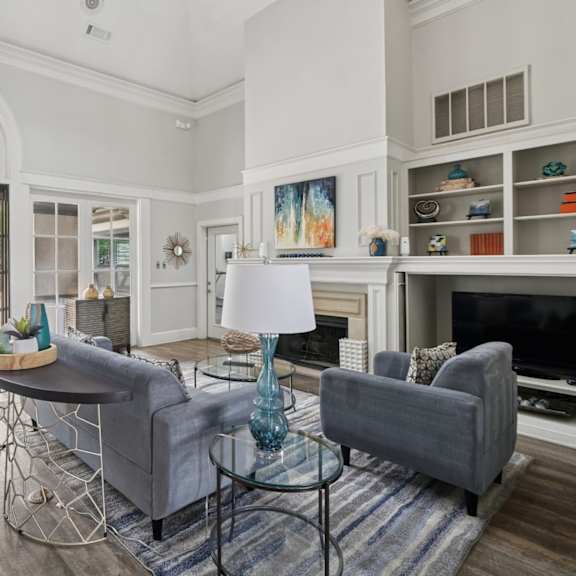 resident lounge area with grey couches and a glass table at jefferson place apartments in irving, tx