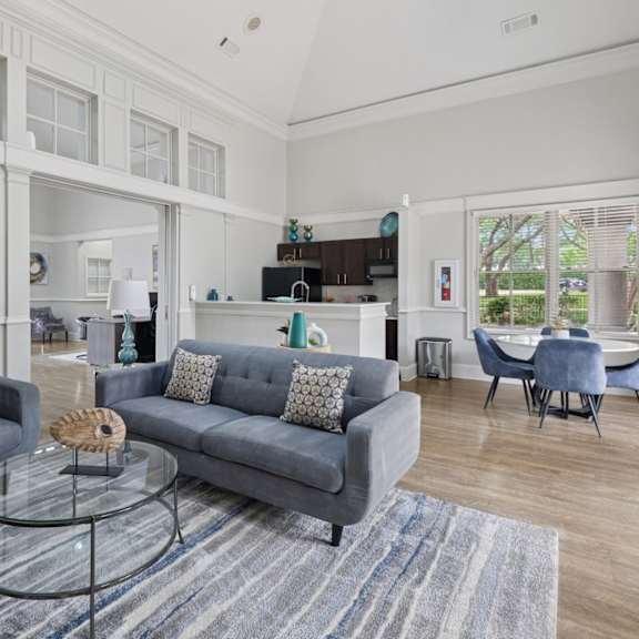 resident lounge with grey couches, a glass coffee table, and a gray rug at jefferson place apartments in irving, tx