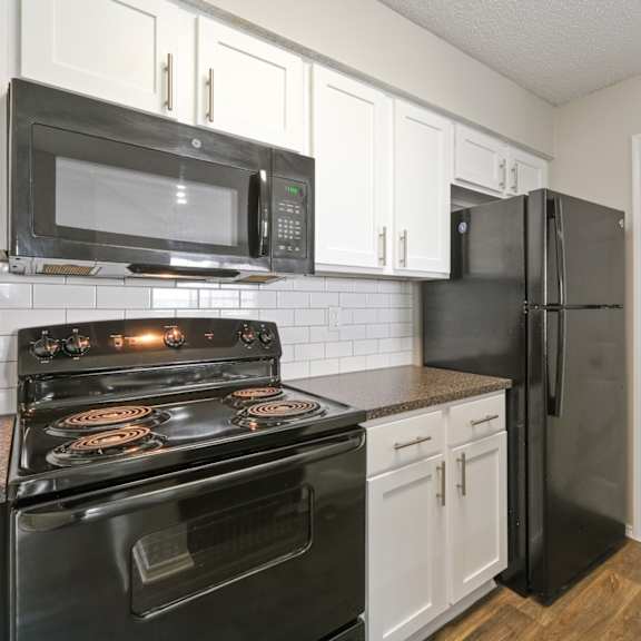 b2 kitchen with black appliances and white cabinets at jefferson place apartments in irving, tx