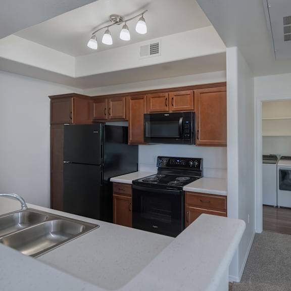 Thumbnail 3 of 4 A kitchen with black appliances and wooden cabinets.