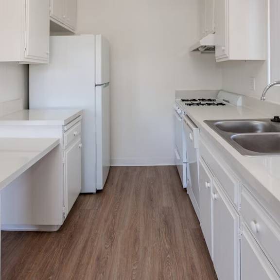 a white kitchen with a sink and a stove.