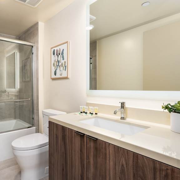 bathroom with tub shower combo and marble countertop at lido - 1532 brockton ave apartments, los angeles, 90025