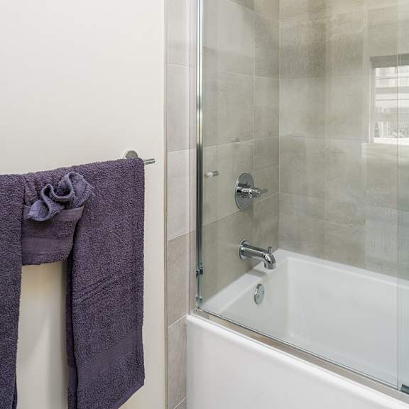 bathroom with tub shower and glass doors at lido - 1532 brockton ave apartments, los angeles
