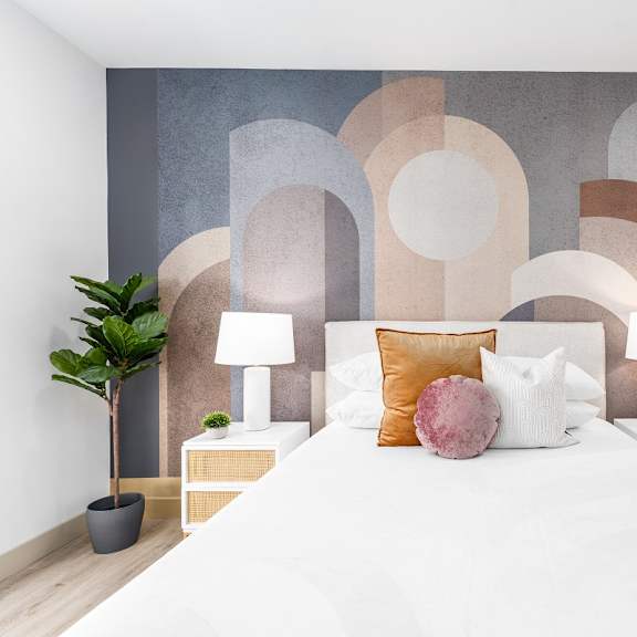 bedroom with abstract wall mural and white bedding at lido - 1532 brockton ave apartments, los angeles, california