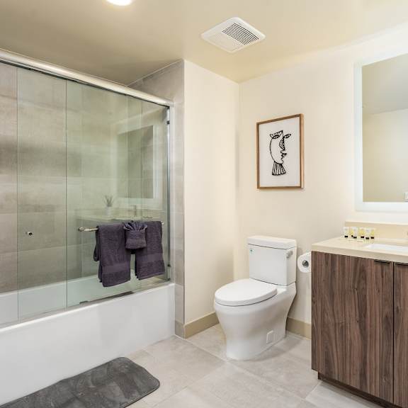 bathroom with glass shower doors and floating vanity at lido - 1532 brockton ave apartments, california