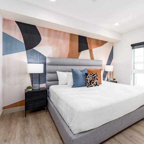 contemporary bedroom with colorful geometric accent wall at lido - 1532 brockton ave apartments, los angeles, california