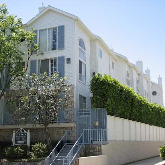 a white building with a green hedge on the side.