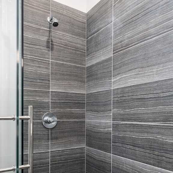 a tiled bathroom with a shower and a glass door at lido apartments - 4025 grandview, california, 90066