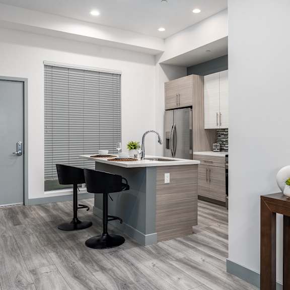 a kitchen with an island and a bar with two black stools at lido apartments - 4025 grandview, culver city, 90066