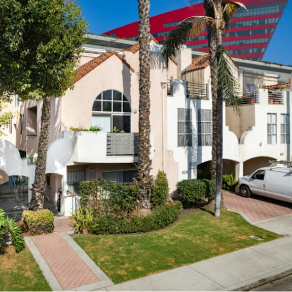 a white building with a red roof and a palm tree in front.
