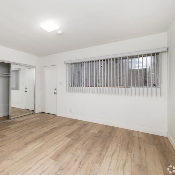 an empty living room with white walls and a sliding glass door to a garage