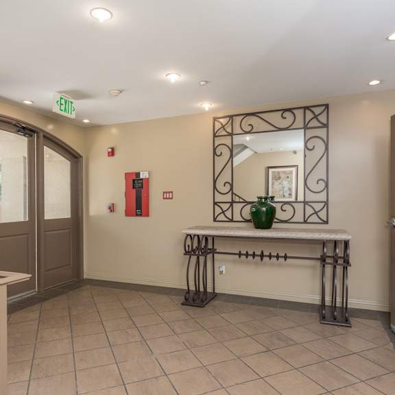 a hallway with a bench, a fire extinguisher, and a mirror.