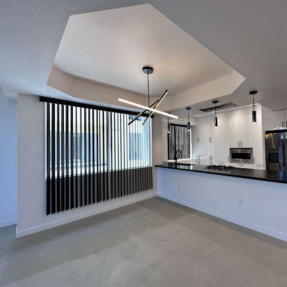 a modern kitchen with a large island and a window with vertical blinds.