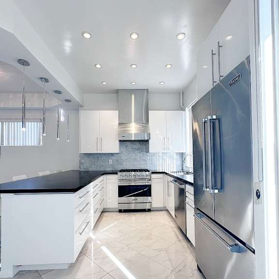 a modern kitchen with a stainless steel refrigerator and white cabinets.