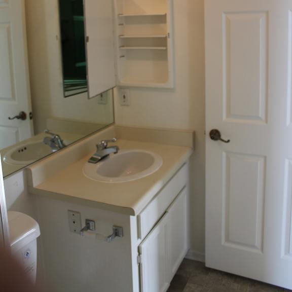 a white bathroom with a toilet, sink, and mirror.