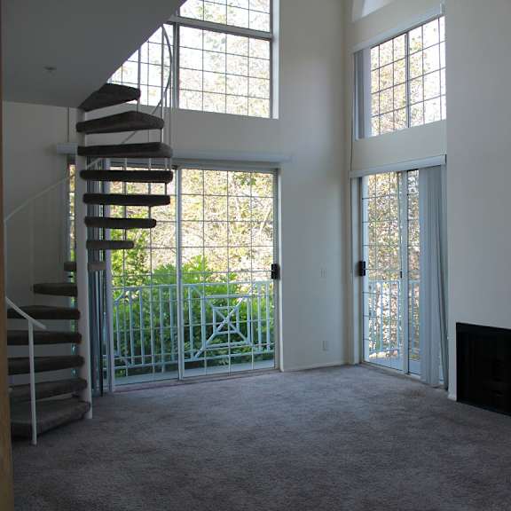 a large empty room with a spiral staircase and a fireplace.