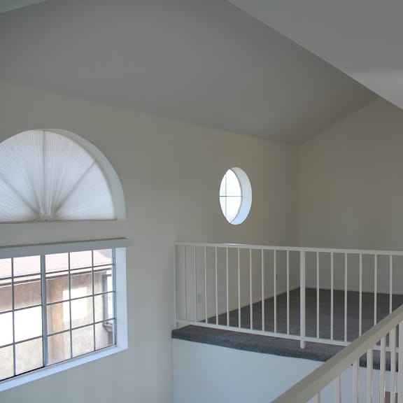 a room with a white railing and a round window.