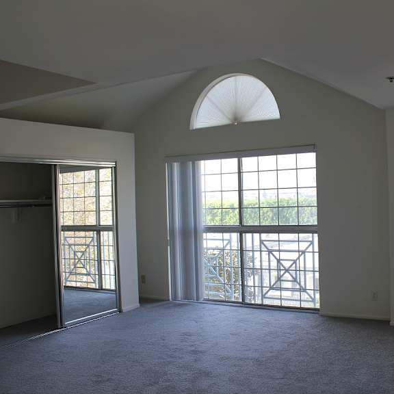 a room with a large window and a balcony with a railing.
