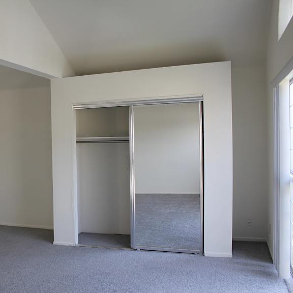 a room with a grey carpet and a white wall with a closet.