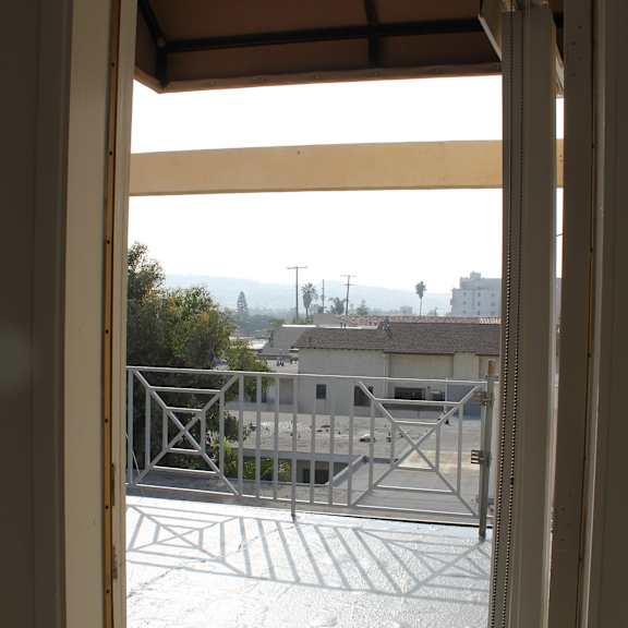 a view from inside a room looking out through an open door to a balcony.