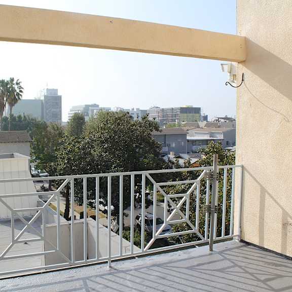 a balcony with a metal railing and a view of the city.