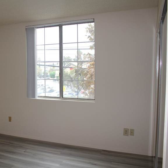 a room with a large window and wooden flooring.