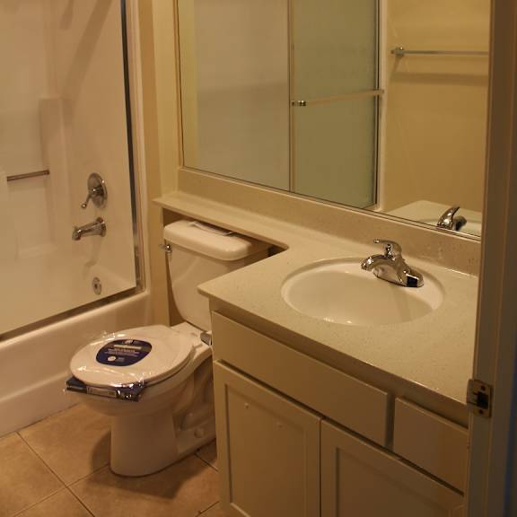 a white toilet with a blue lid is in a bathroom with a sink and mirror.