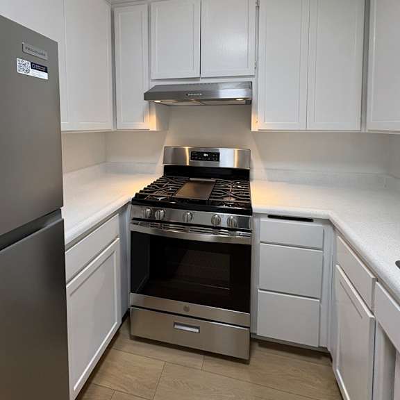 a modern kitchen with white cabinets and stainless steel appliances.