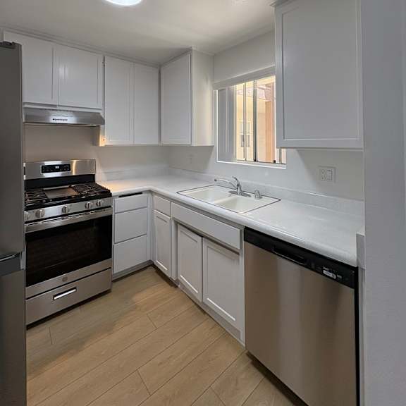 a kitchen with white cabinets and stainless steel appliances.