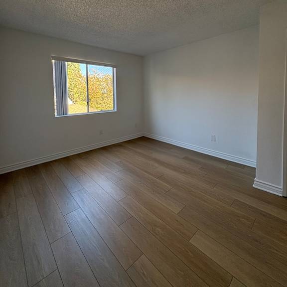 a room with a window and wooden flooring.