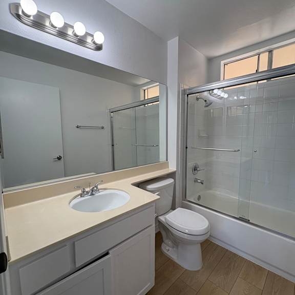 a bathroom with a sink, toilet, and mirror.