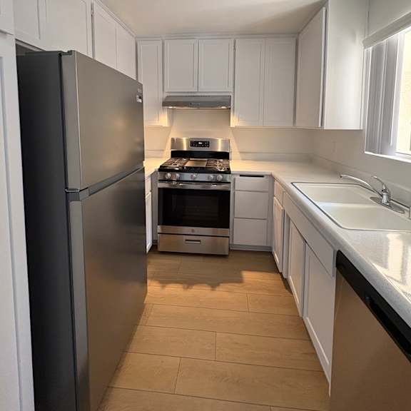 a kitchen with white cabinets and a black refrigerator.