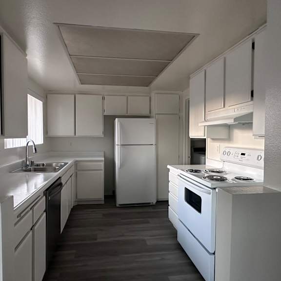 a white kitchen with a refrigerator, oven, and sink.at lido apartments - 101-197 n ridgeway, anaheim california