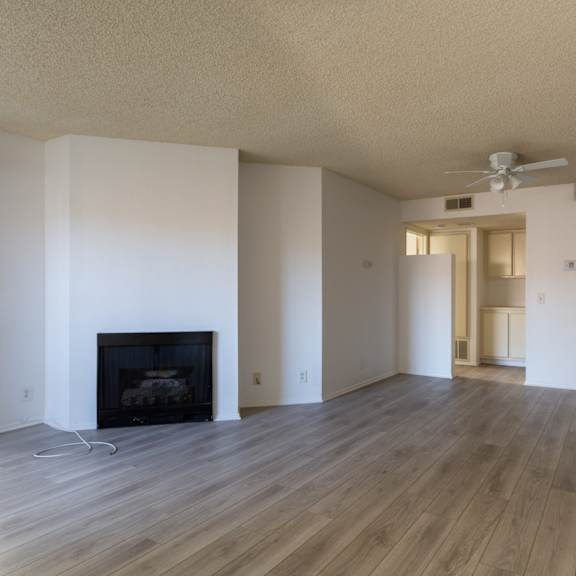 a living room with a fireplace and a fan on the ceiling.at lido apartments - 101-197 n ridgeway, anaheim, ca 92801