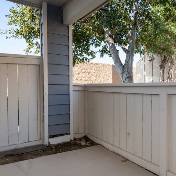 a white wooden deck with a tree in the background at lido apartments - 101-197 n ridgeway, anaheim, ca