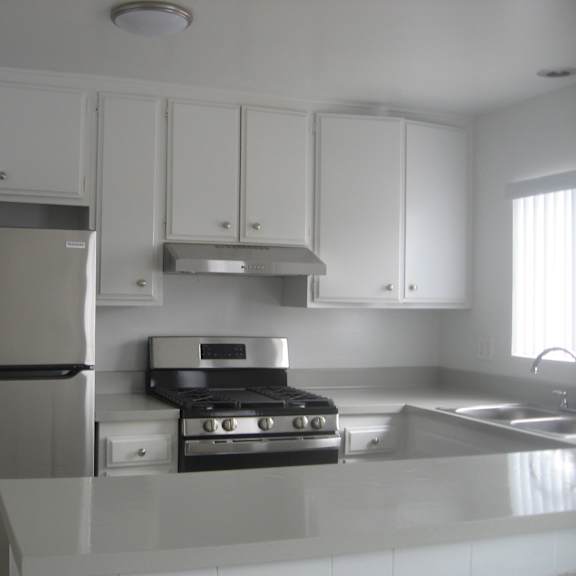 a kitchen with white cabinets and stainless steel appliances.